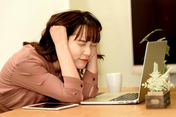 精神的なストレスによってアドレナリンが分泌され頭痛が起こってしまっている女性のイメージ