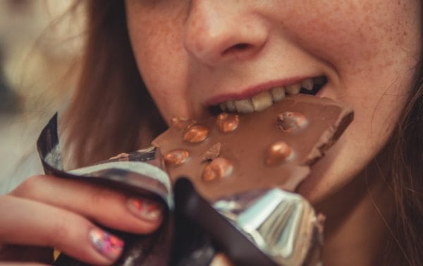 カラダに悪いというハリボーを食べた後に太るチョコレートを食べている女の子のイメージ