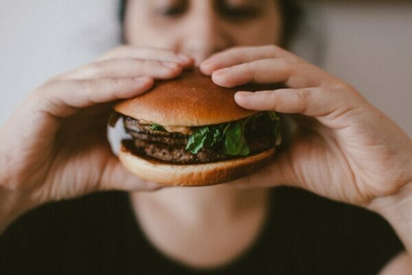 消化に悪いハンバーガーを食べている人のイメージ