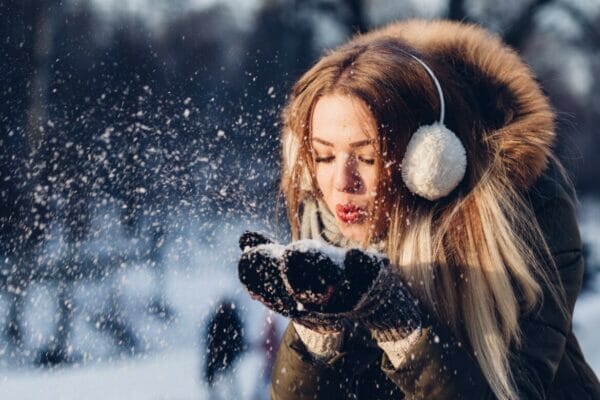 寒い冬に粉雪で遊ぶ女性のイメージ