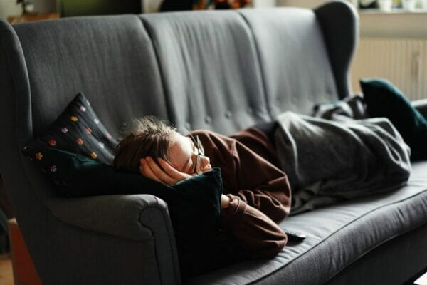 リラックスモードで寝ようとソファでくつろいでいる女性のイメージ