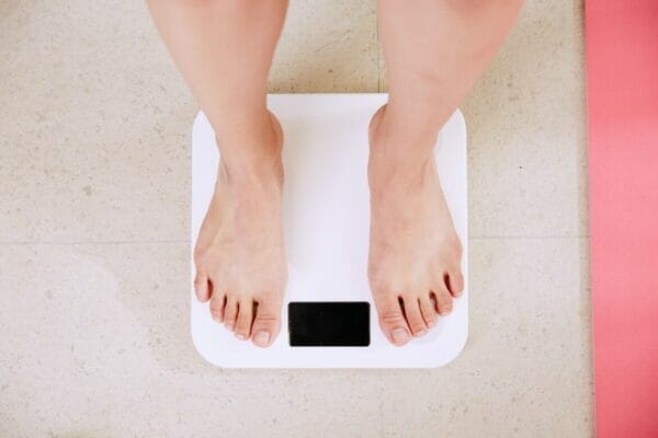 何度もリバウンドして痩せにくくなった人が体重計に乗っているイメージ
